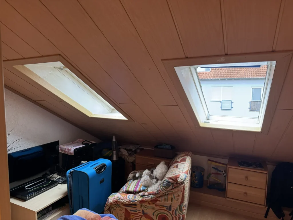 Vorher: Dachzimmer mit zwei kleinen Dachfenstern und dunkler Holzdecke